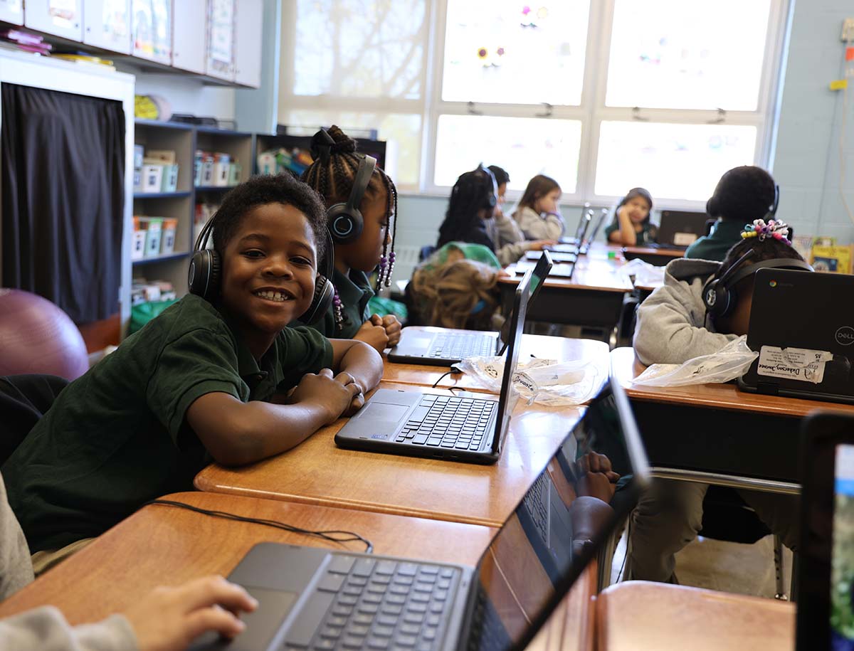 Elementary student smiling and posing together in a classroom.